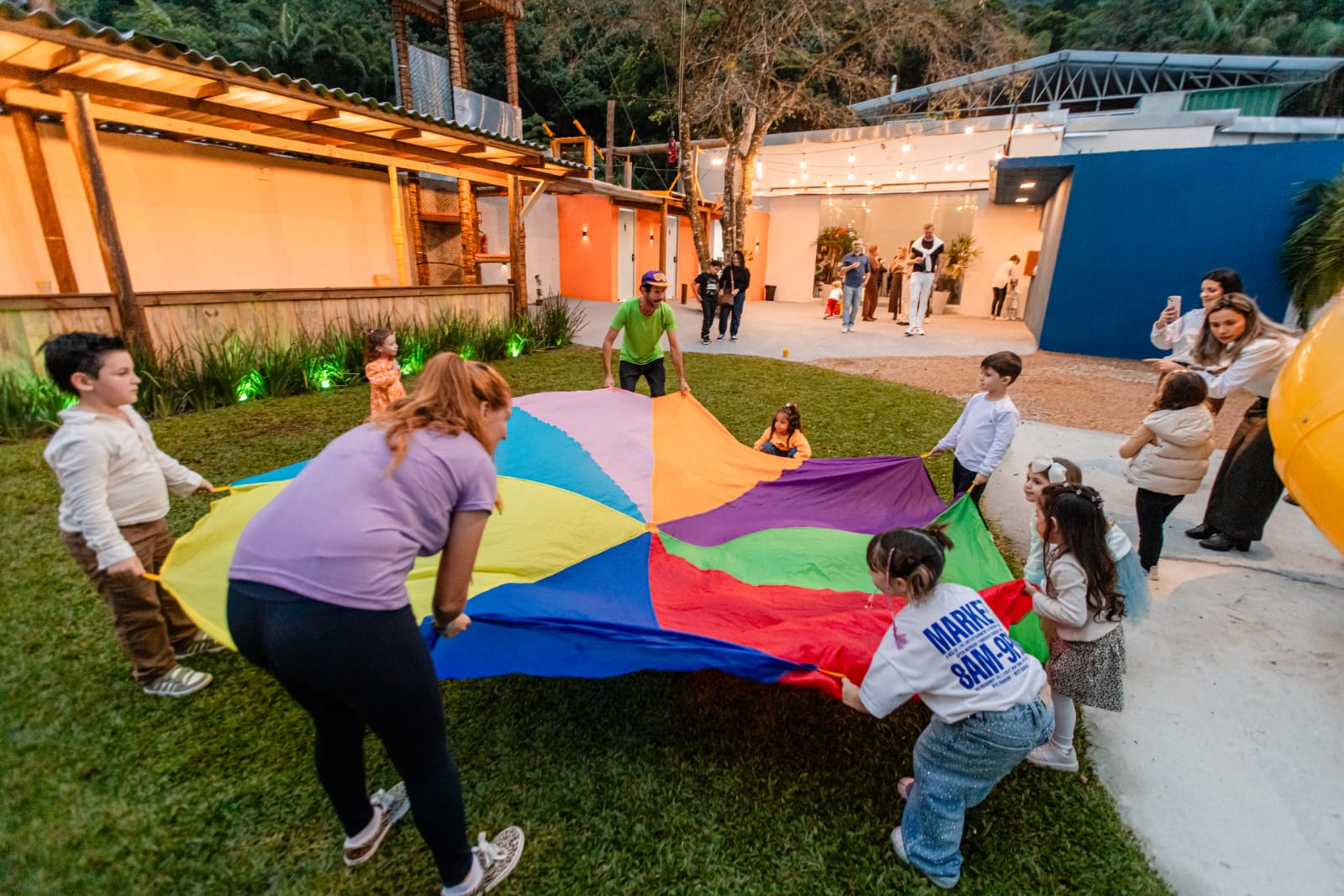 Recreação ao ar livre com paraquedas colorido e crianças brincando
